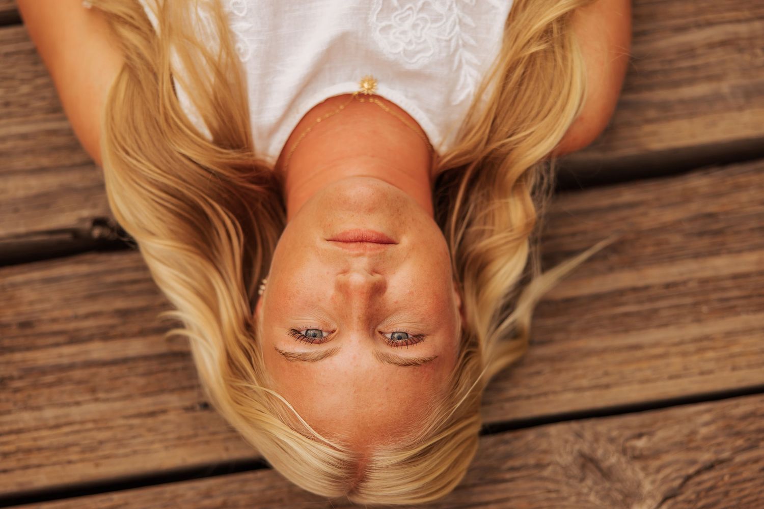 Overhead view portrait on wooden deck with long blonde hair spread out.
