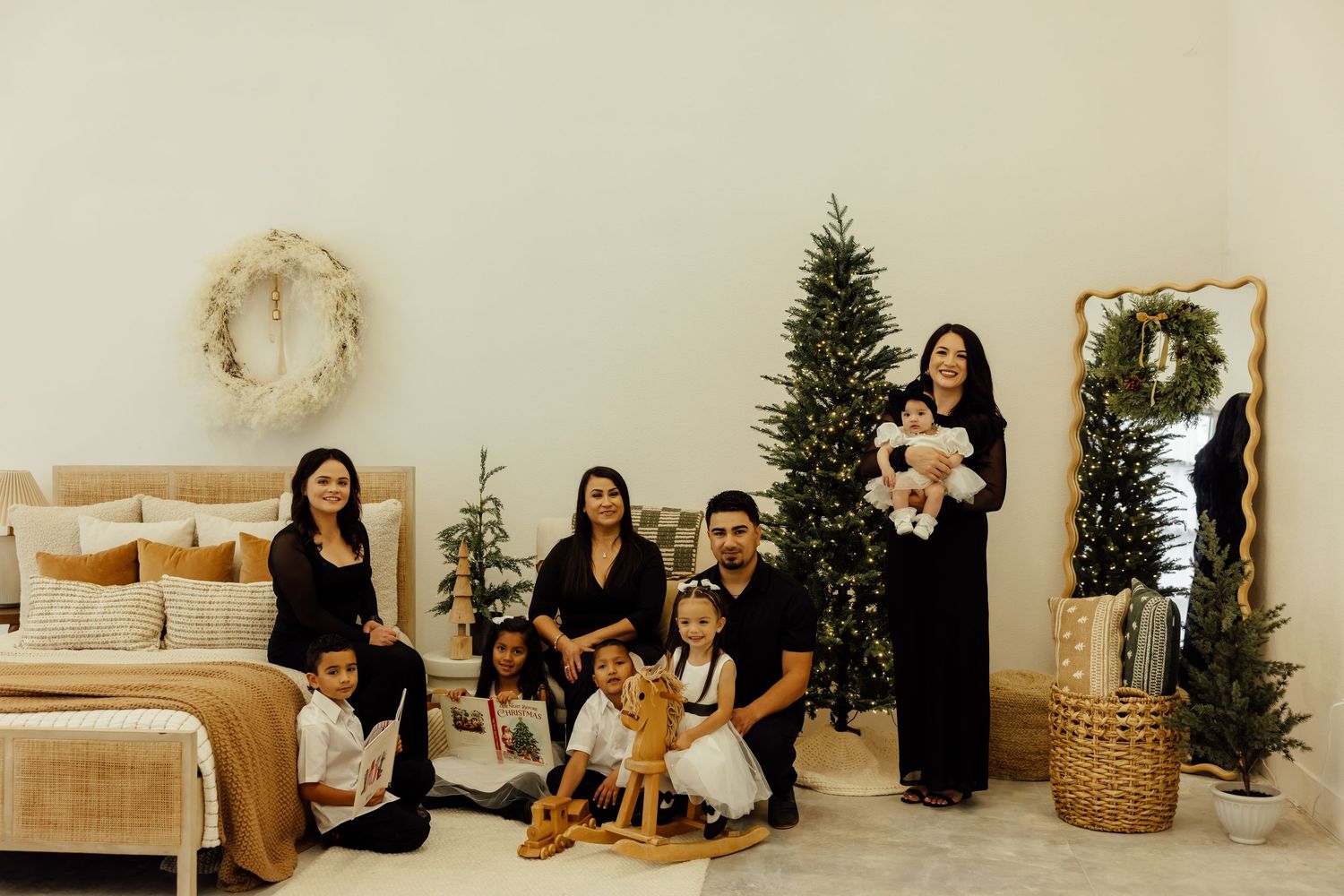 Indoor family photo session with minimal white decor and Christmas tree in background.