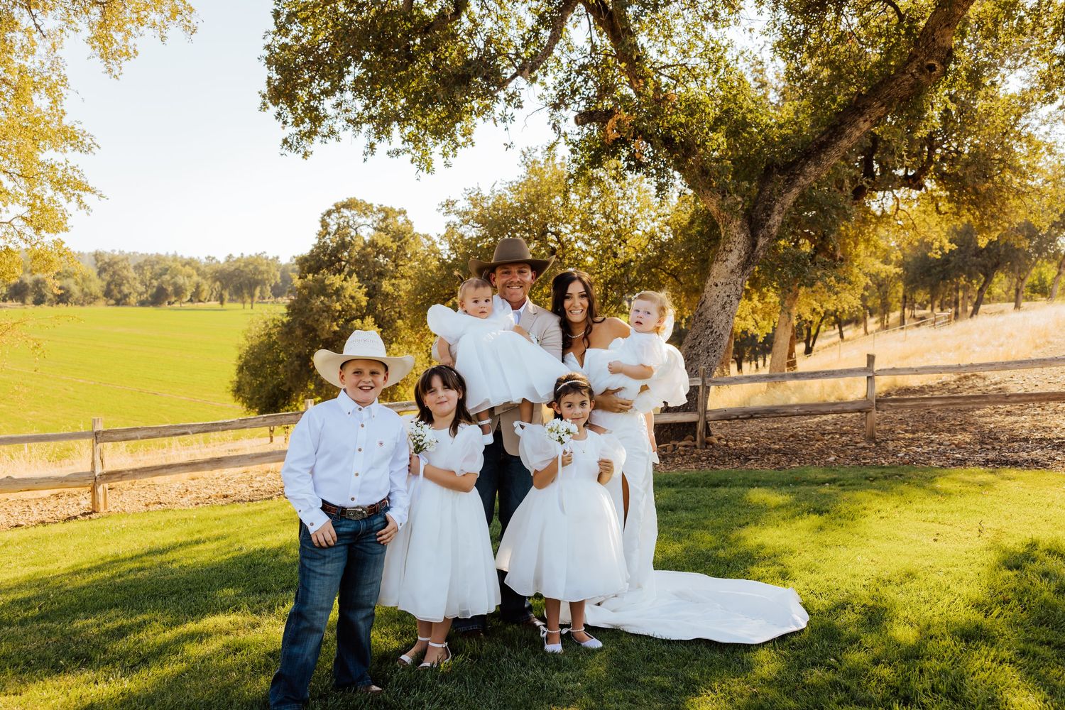 Wedding party poses playfully in a scenic outdoor setting with golden trees and rolling hills.