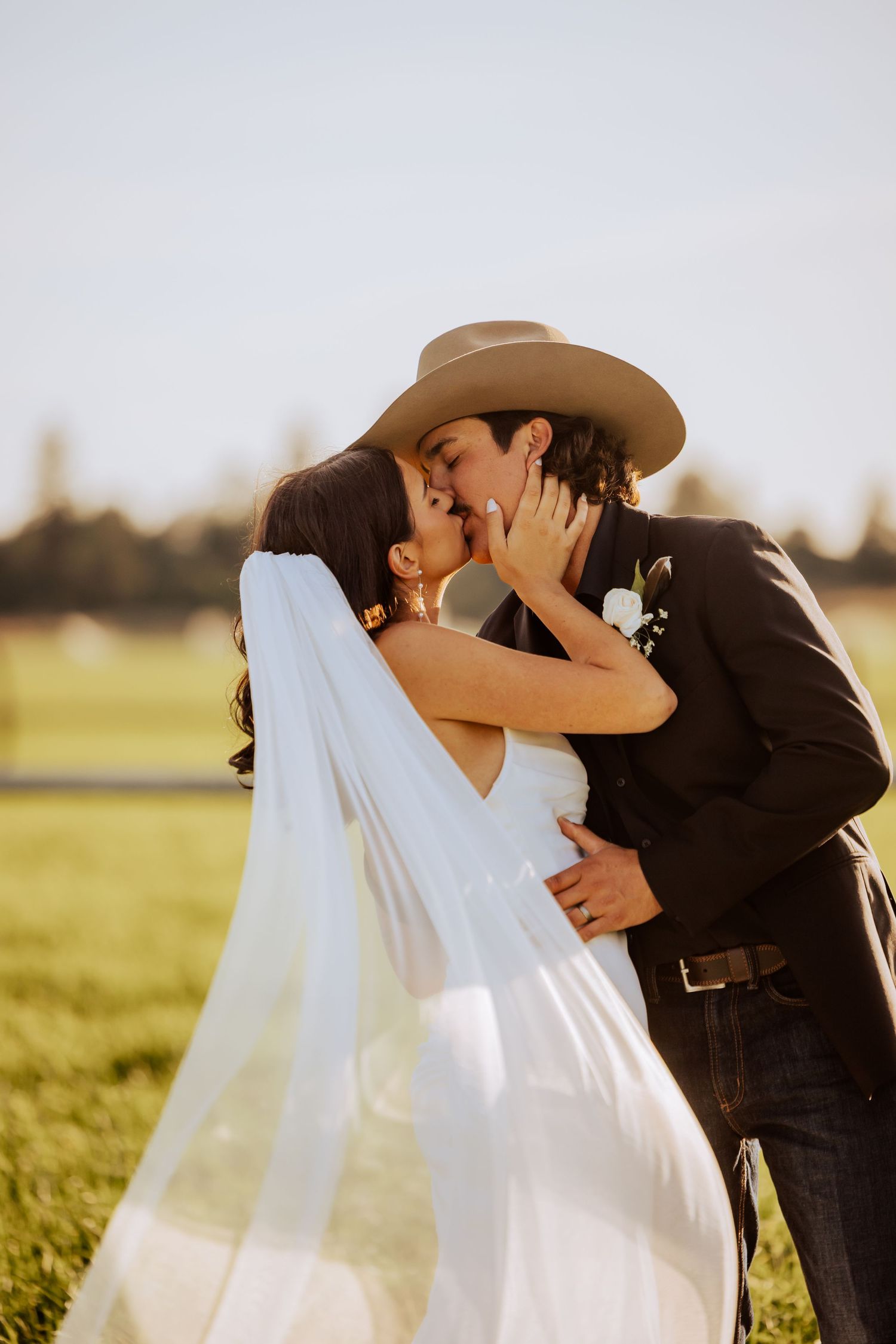 Romantic wedding couple shares intimate moments in a sun-drenched field.