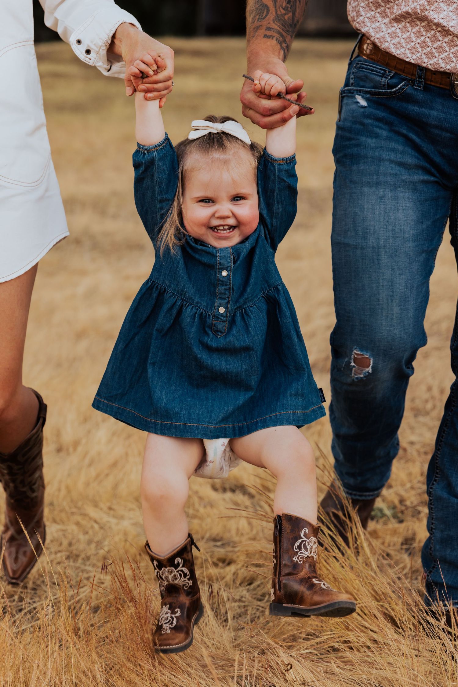 Close-up of boots and denim outfits while walking through golden grass field.