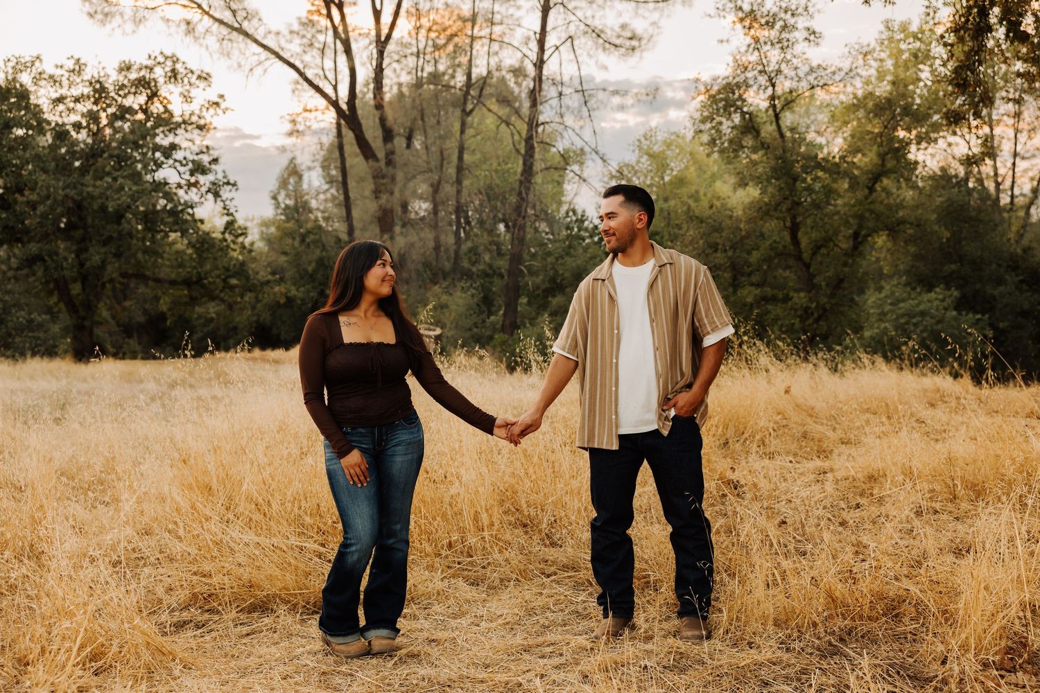 Family walking hand in hand through tall grass at sunset.