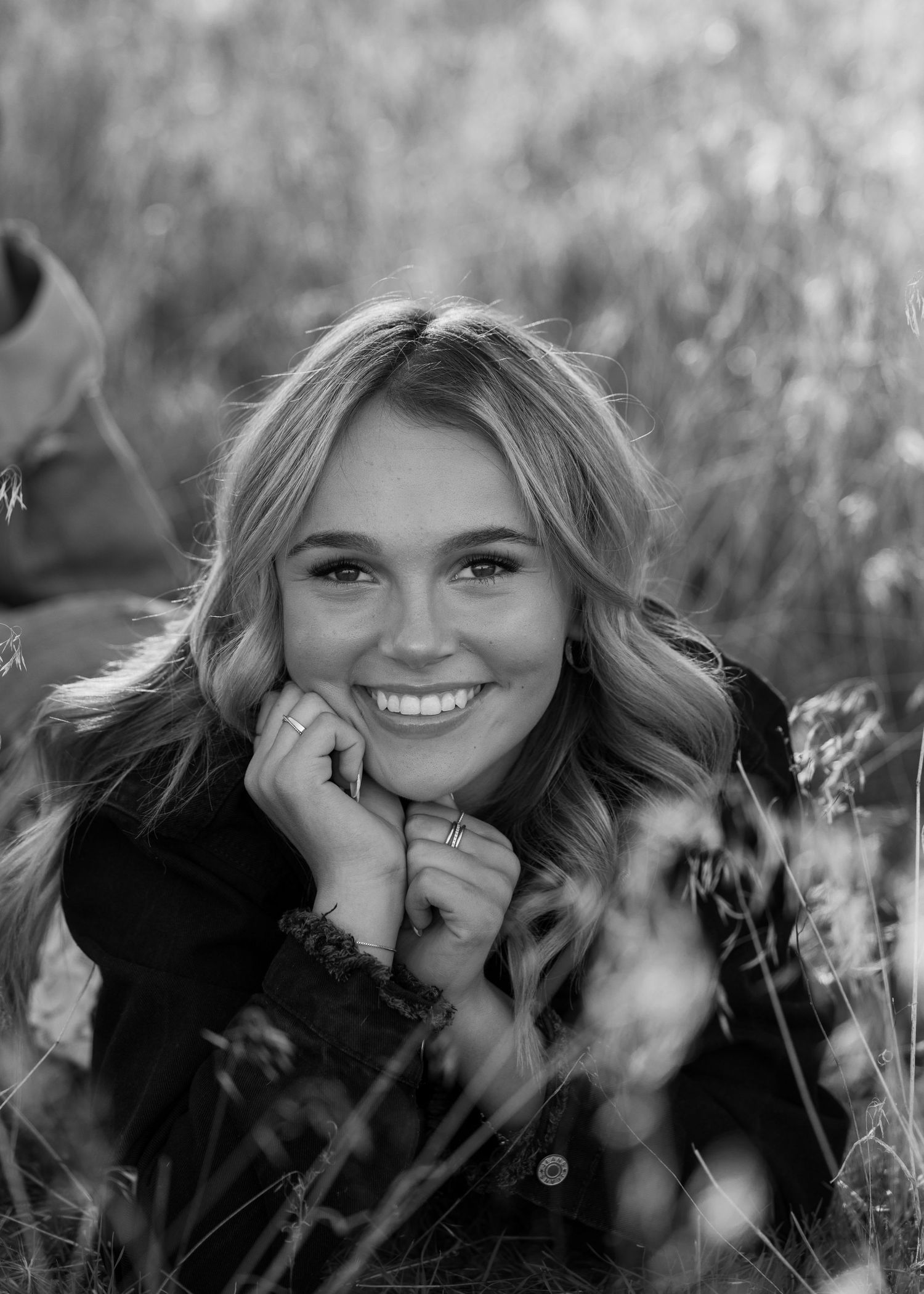 Candid black and white portrait showing joyful expression while resting in outdoor field.