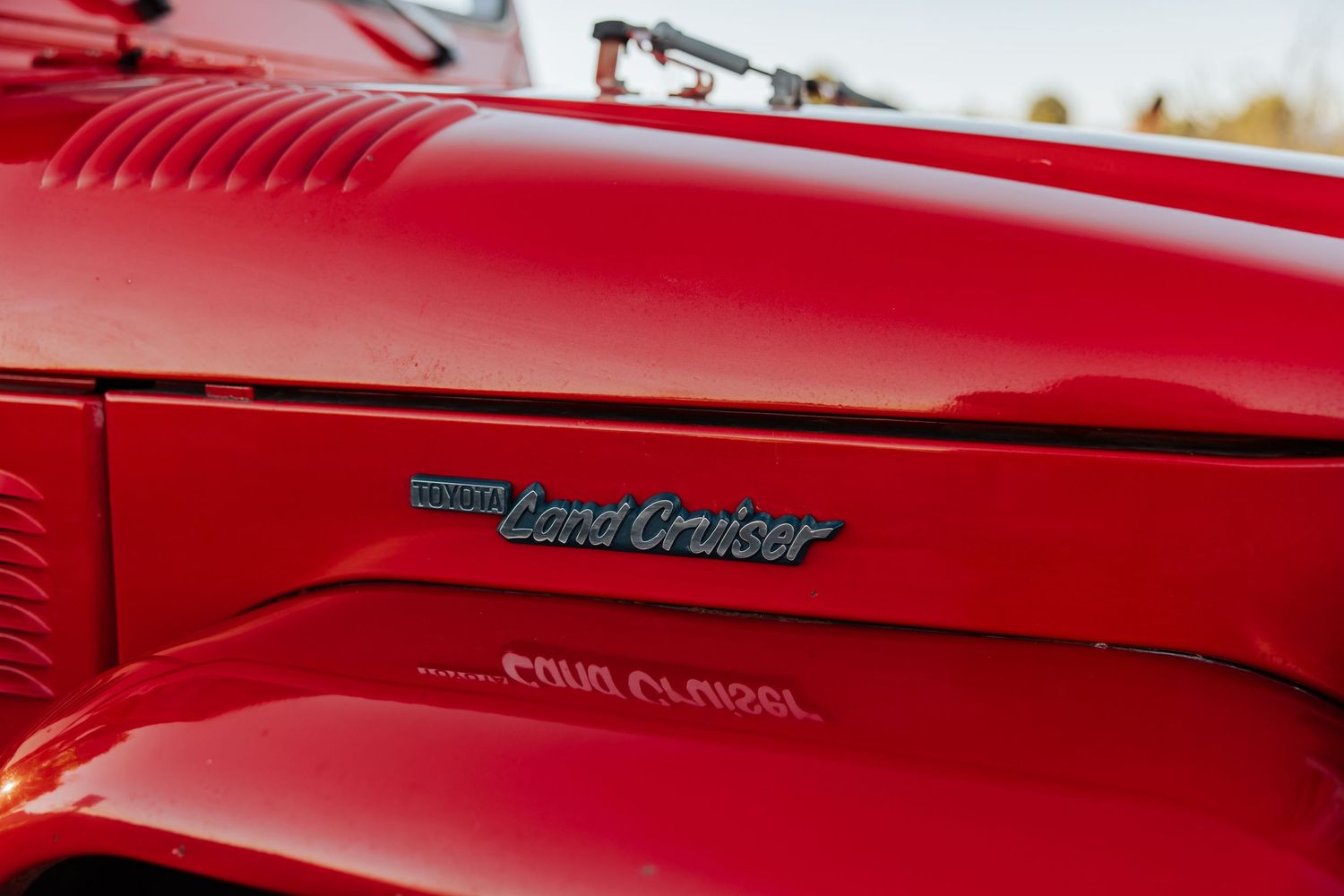 Close-up detail of red classic Land Cruiser exterior badging and paint.