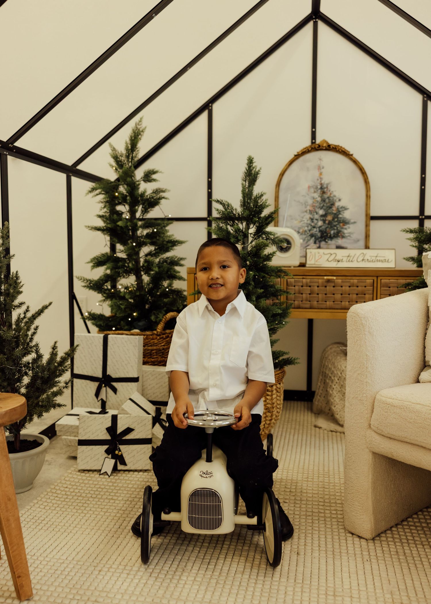 Children playing in a bright room with Christmas decor and white furniture.