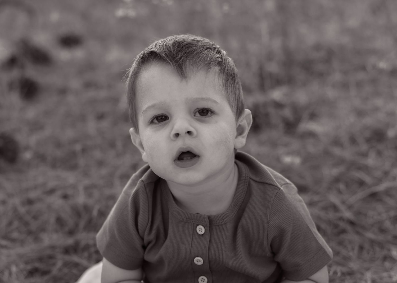 Close-up black and white portrait of a young child wearing a henley shirt.