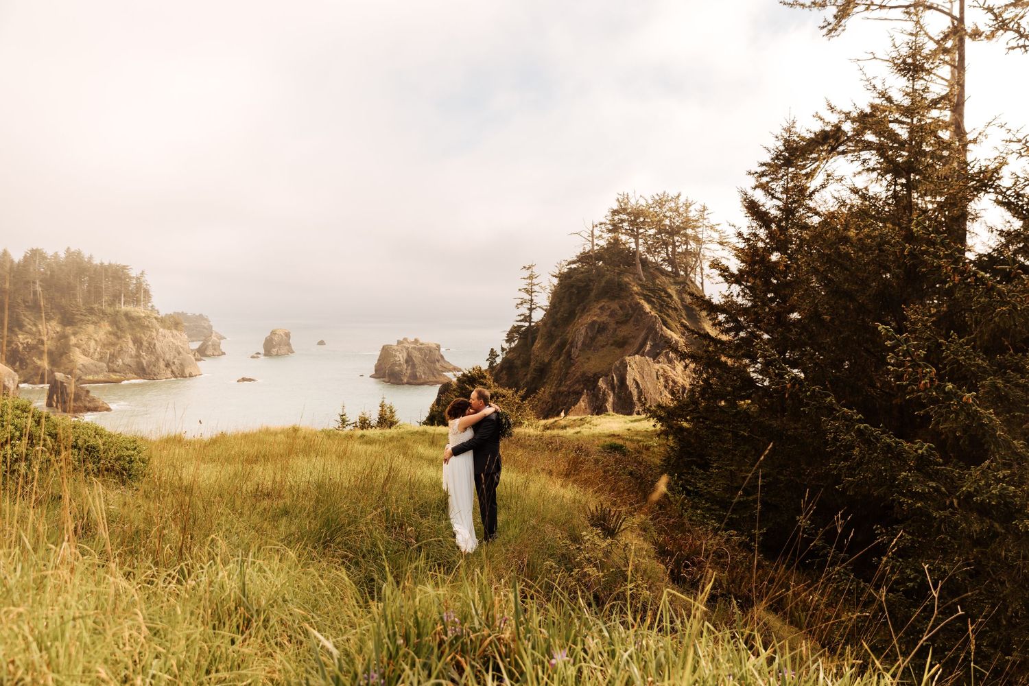 Panoramic coastal wedding photos with couple on cliff overlooking ocean.