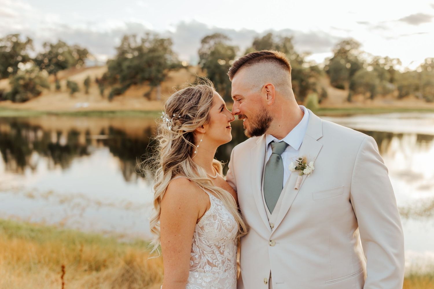 Romantic sunset portraits of wedding couple by lakeside in warm evening light.