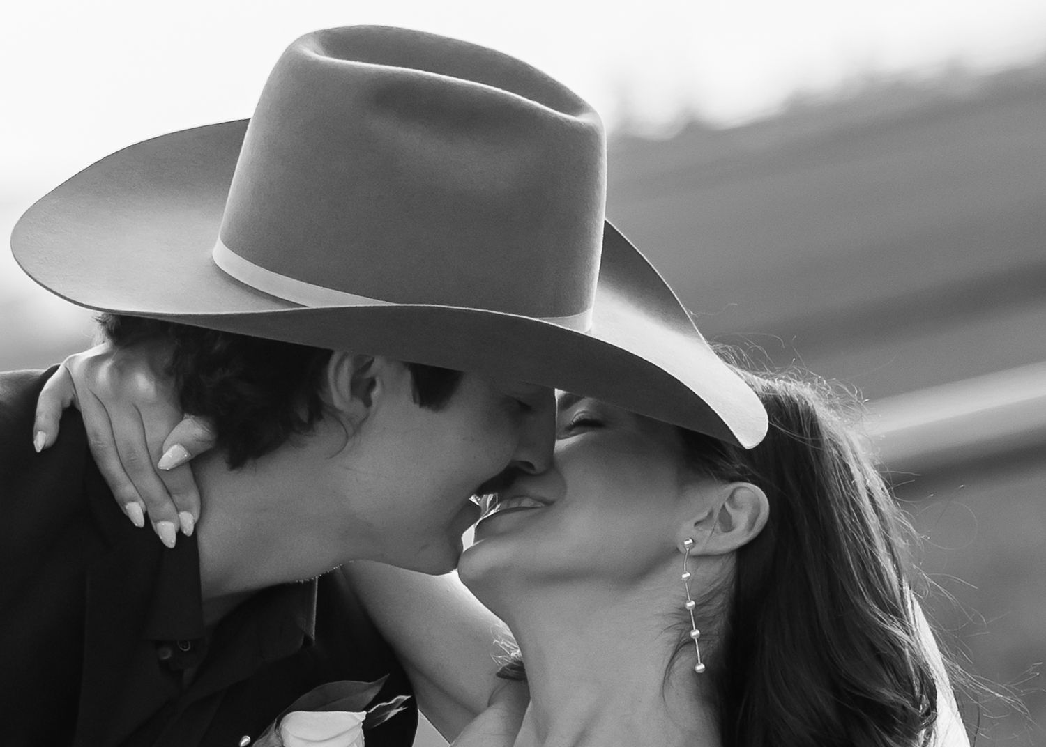 Black and white portrait of couple in western attire sharing an intimate moment.