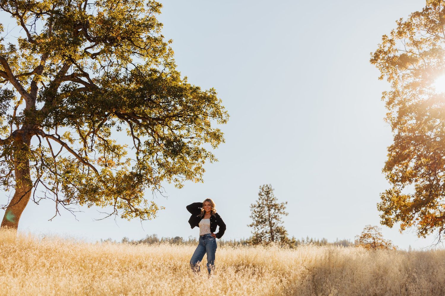 Silhouetted figures on a hillside during golden hour with autumn trees in the background.