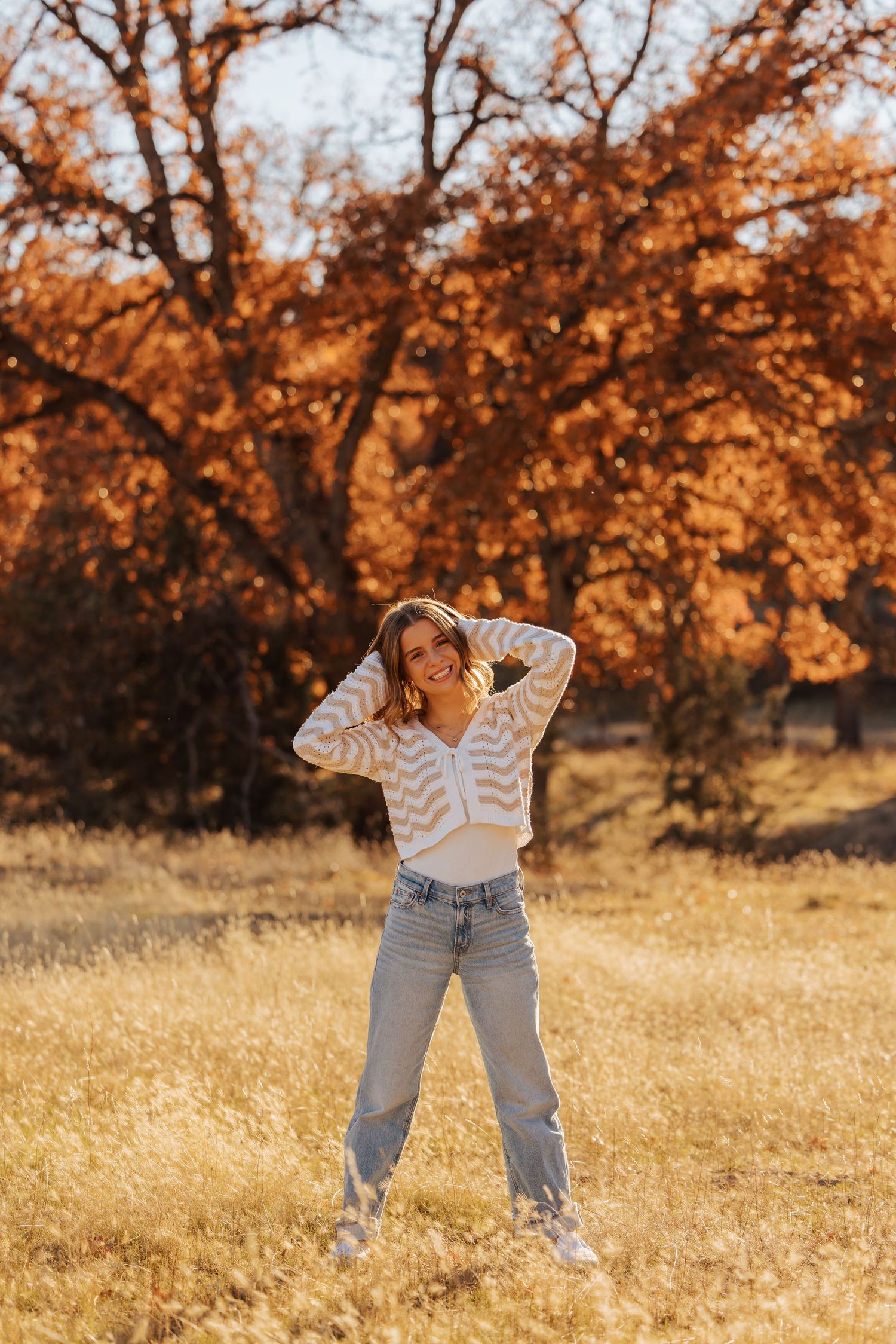 Casual autumn photoshoot in a field with golden trees and warm lighting.