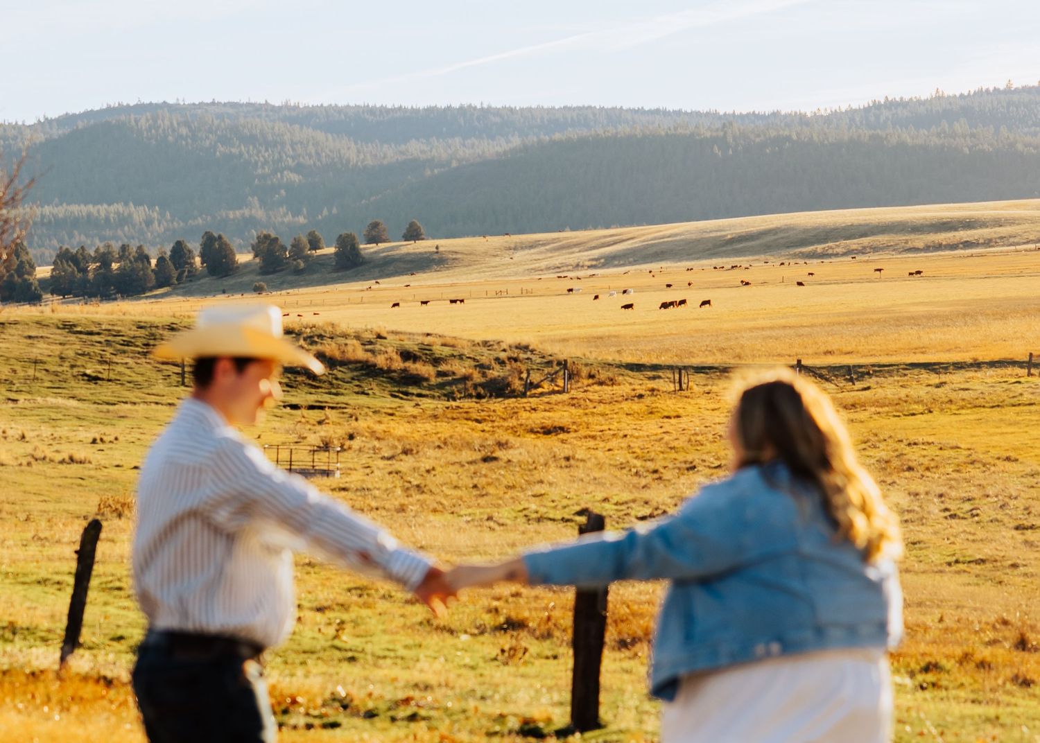 A couple dances in a sunlit field during their engagement session.