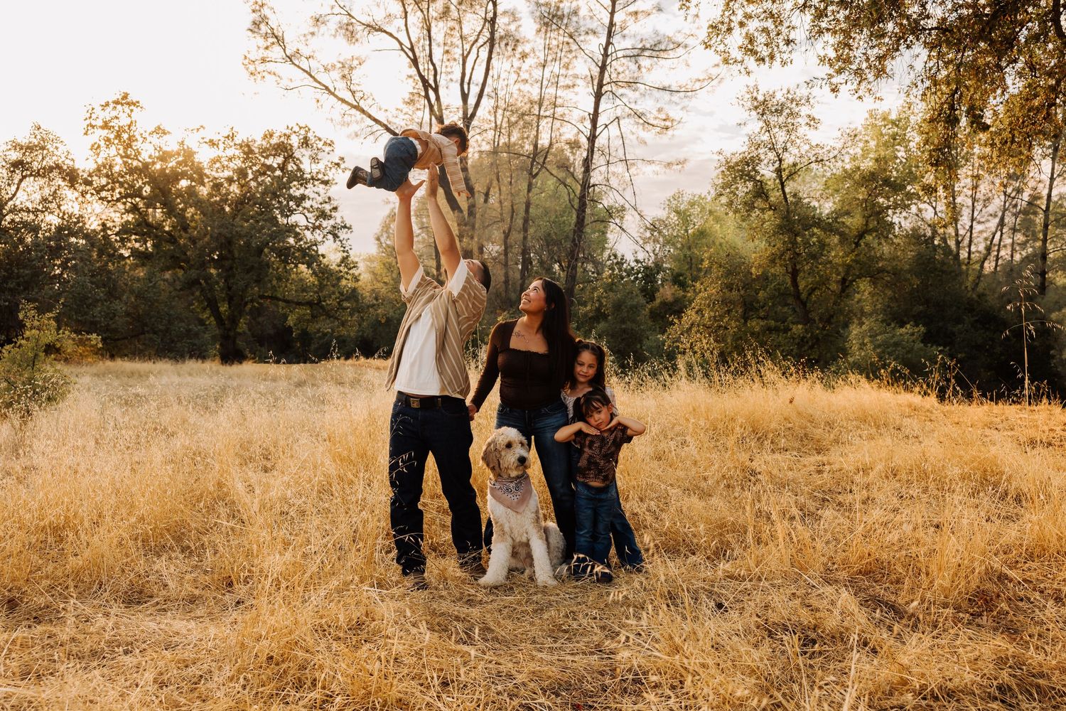 Casual group photo session in golden field with natural backdrop of trees.