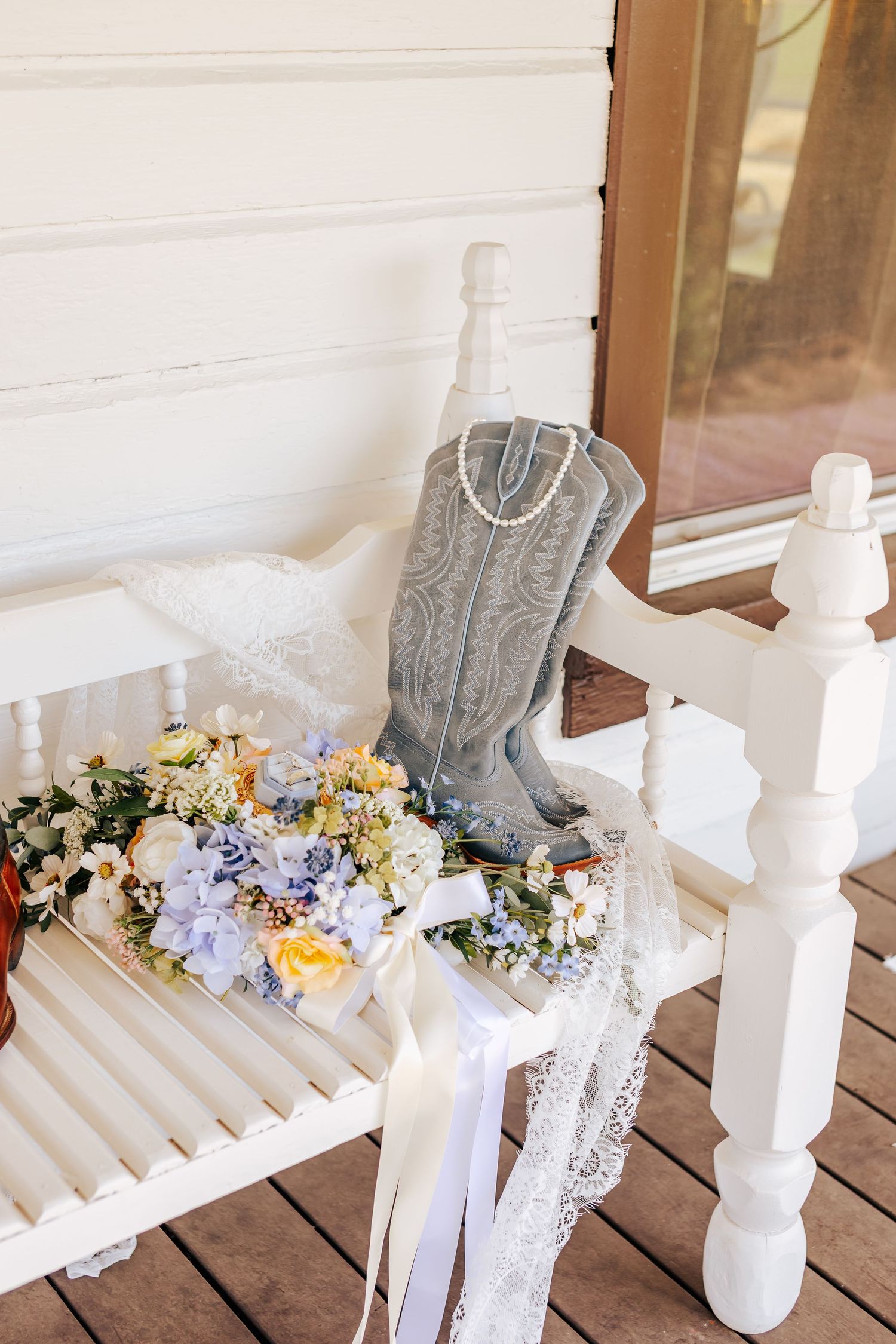 Delicate floral bouquets with yellow roses and blue flowers arranged on a white wooden bench.