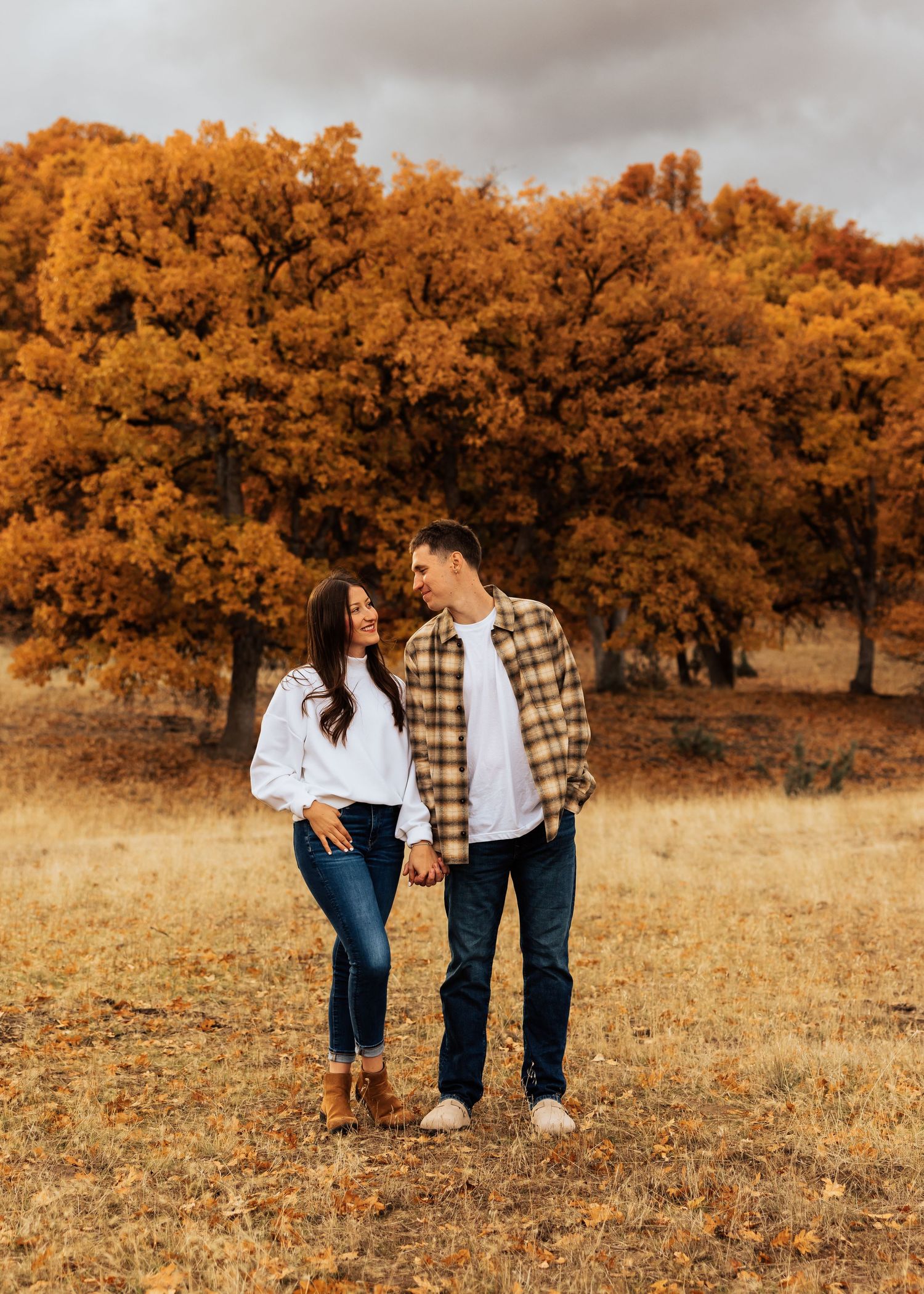 Couple enjoying a tender moment while walking in a field during golden autumn.