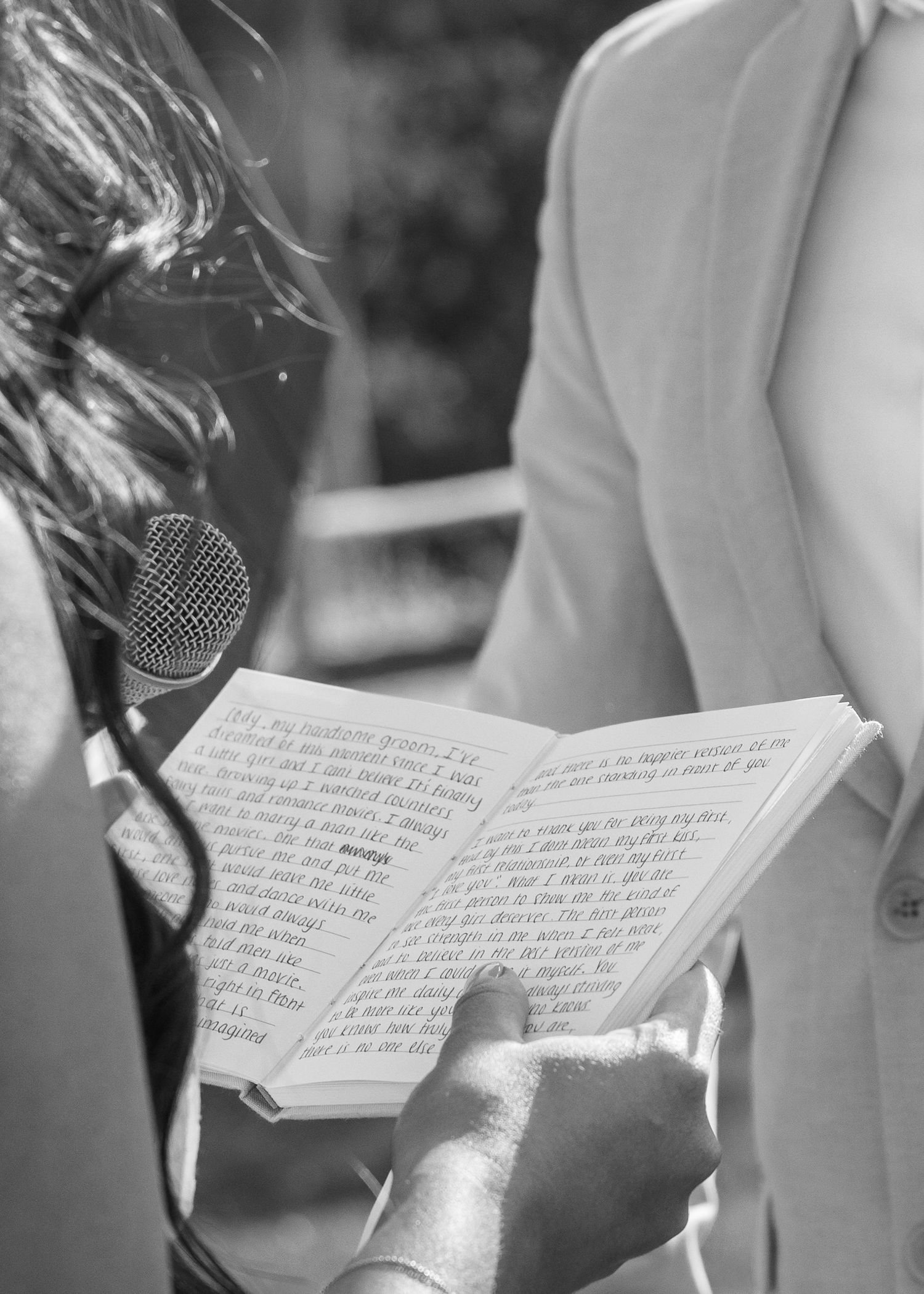 Black and white detail shot of handwritten vows in an open book during wedding ceremony.