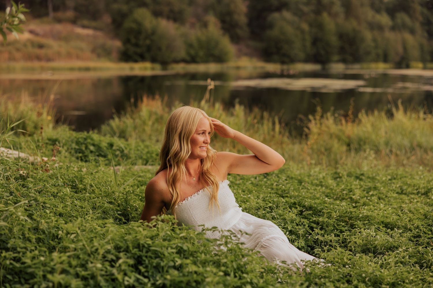Sunset portrait session in a lush green field near water.