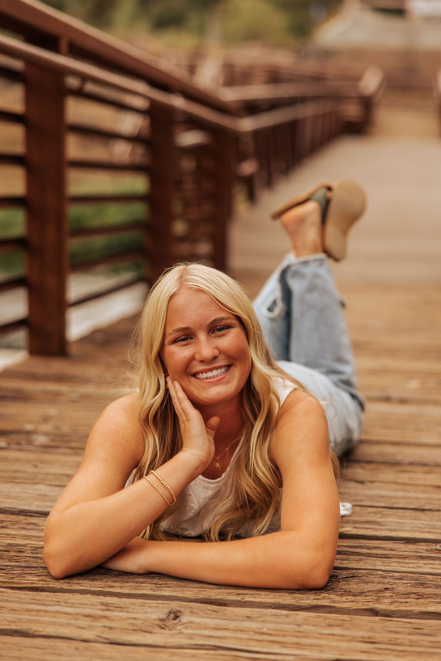 Person lying on wooden deck in casual outdoor photoshoot setting.