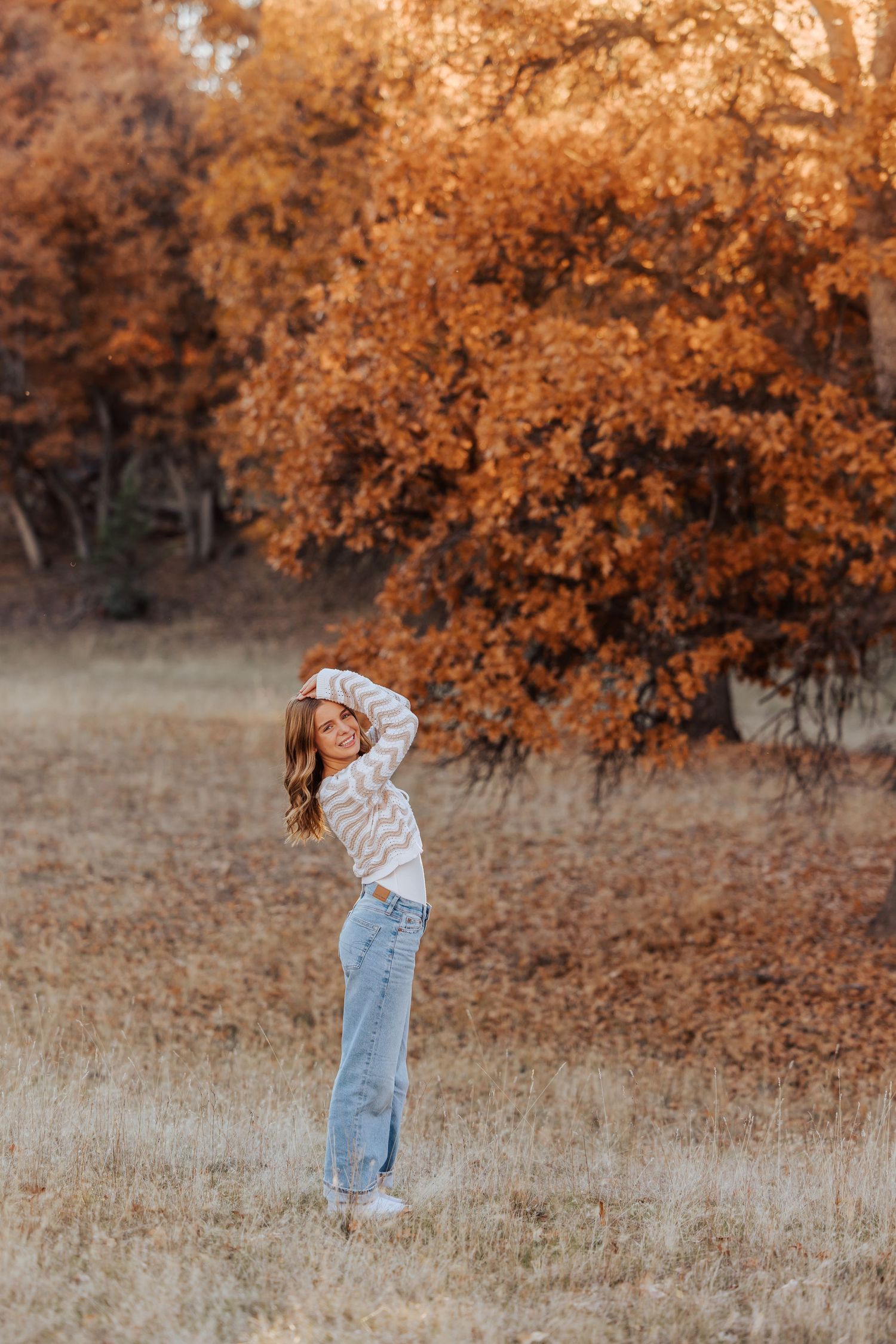 Full-length photo in a field with autumn foliage and golden afternoon light.