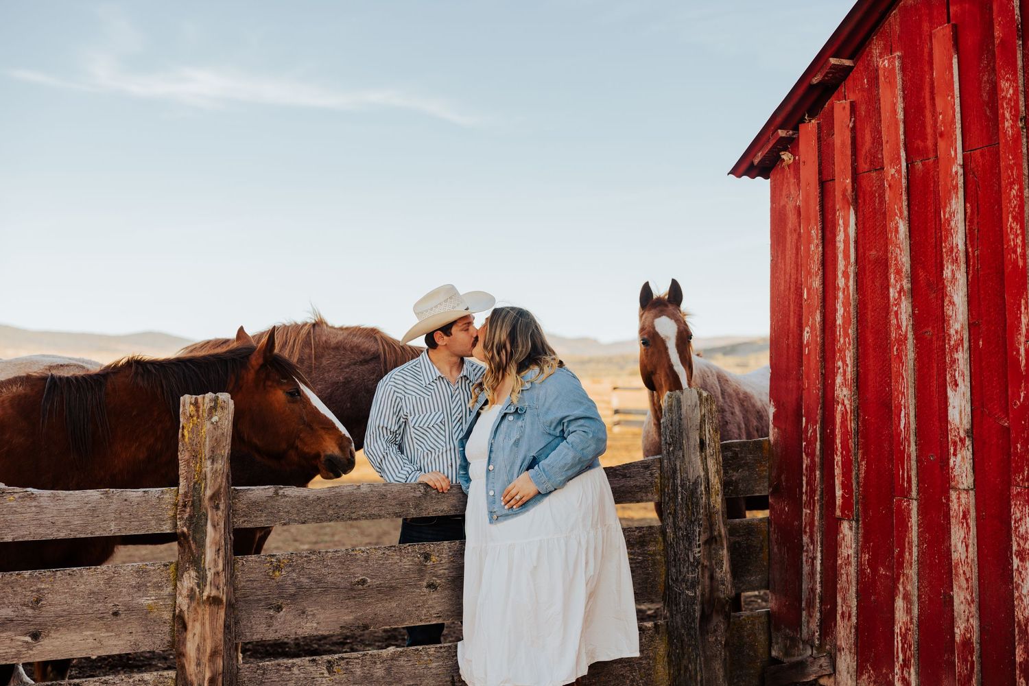 A rustic red barn and wooden fence create a backdrop for a romantic country photoshoot.