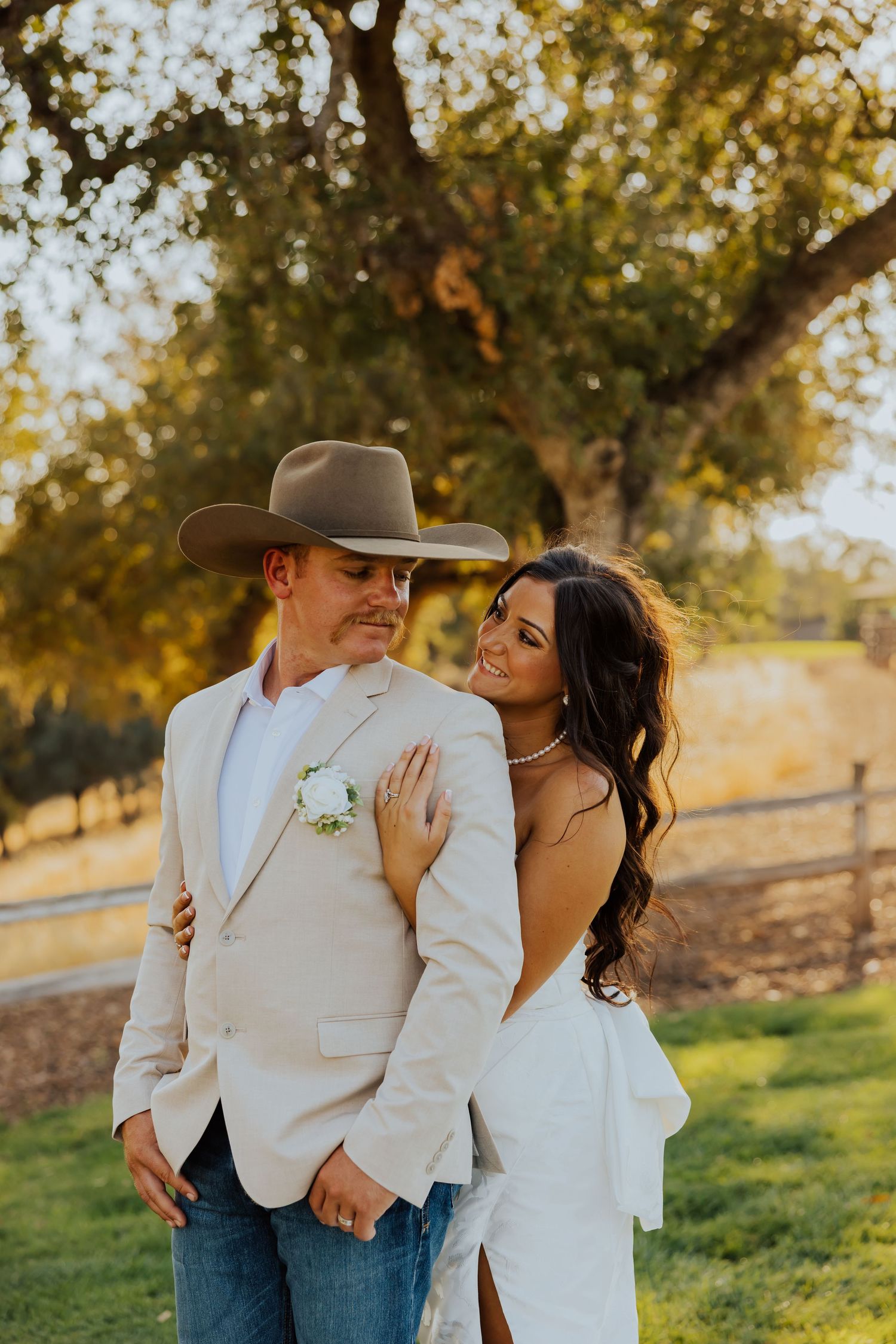 A couple shares intimate moments in a rustic outdoor setting with golden autumn trees in the background.