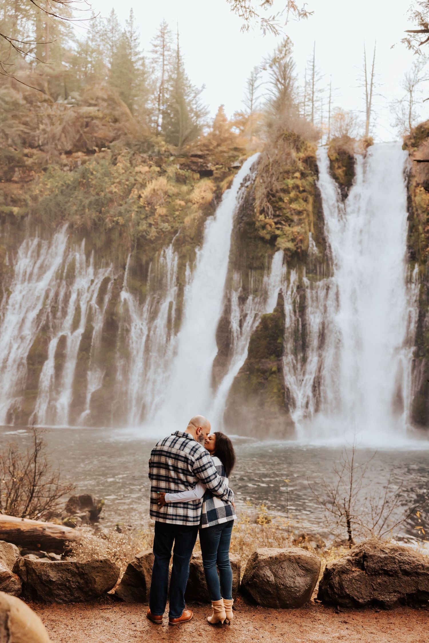 A scenic waterfall cascades down multiple tiers in an autumn forest landscape.