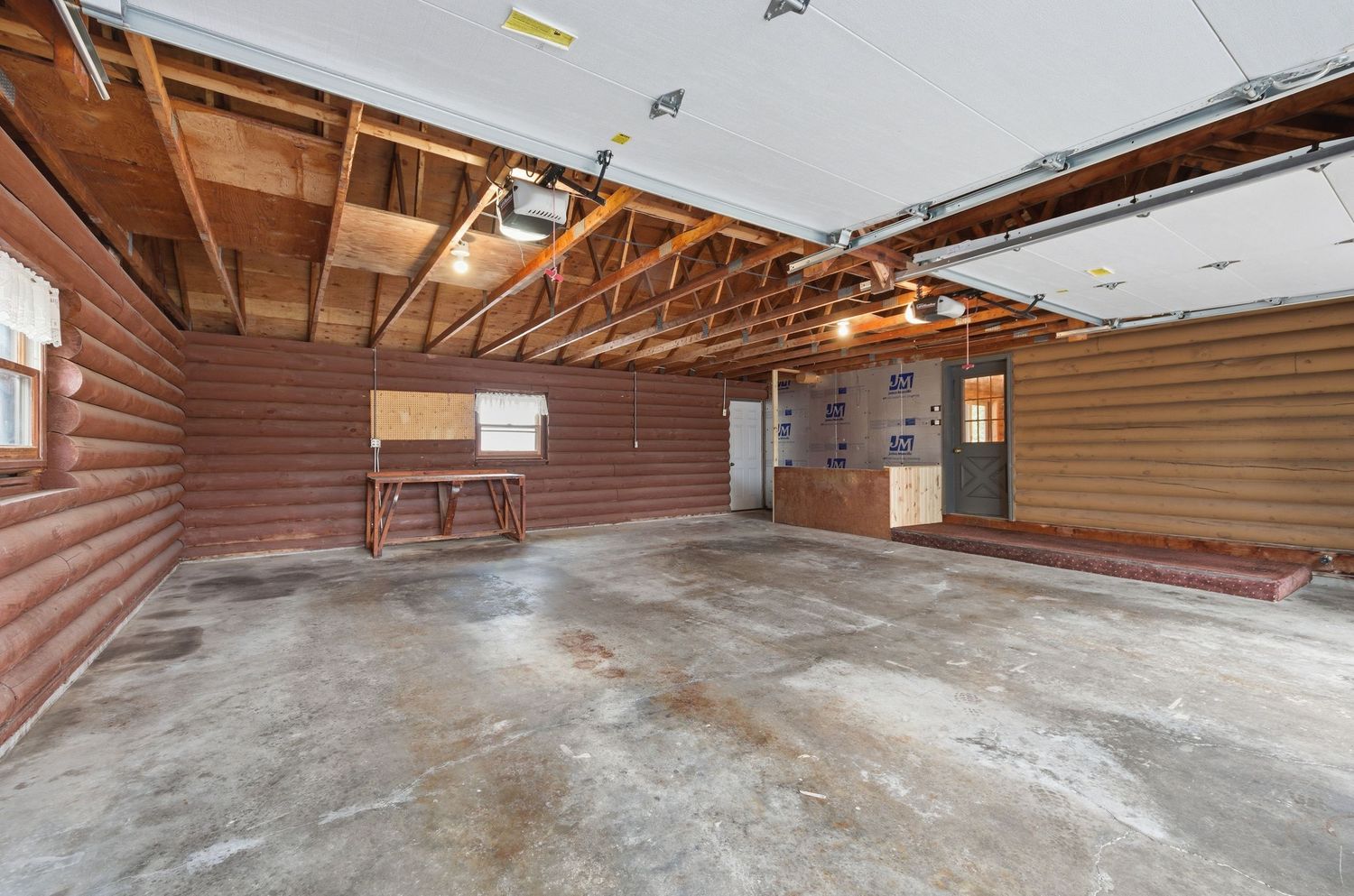 Interior view of an empty commercial warehouse space with exposed wooden beams and concrete flooring.