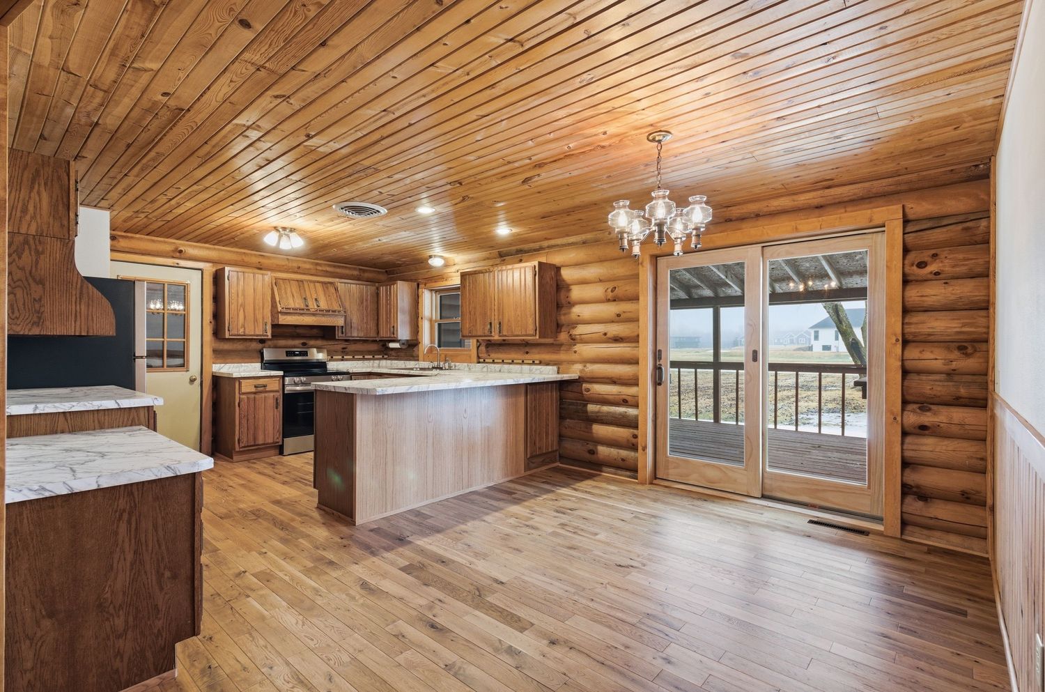 Interior view of a rustic log cabin home with wood paneled walls and ceiling featuring modern lighting fixtures.
