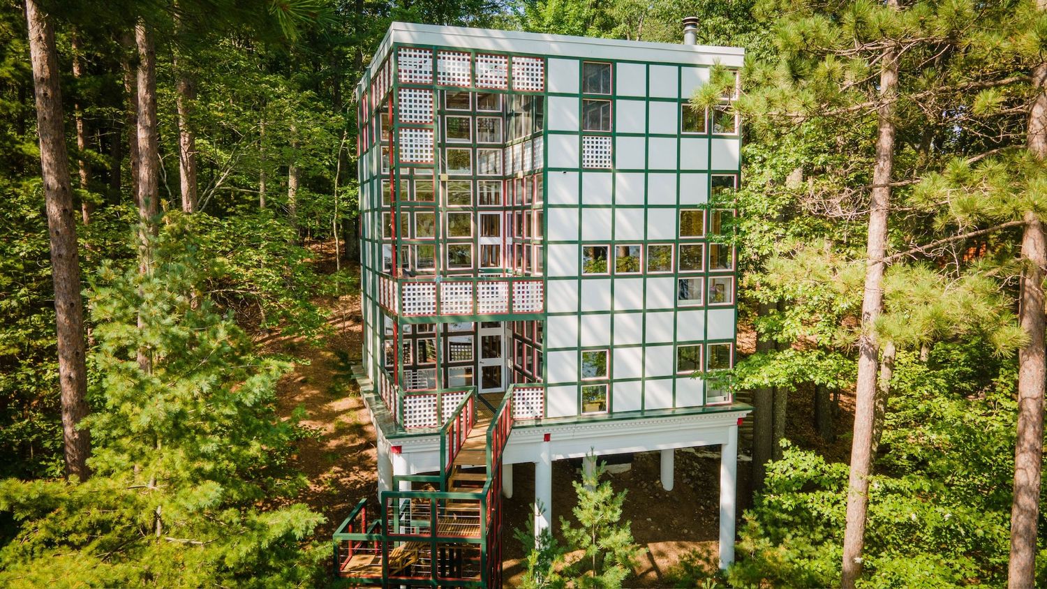 Modern glass house with multiple levels nestled in a lush forest setting creates a stunning architectural statement. Hewitt WI