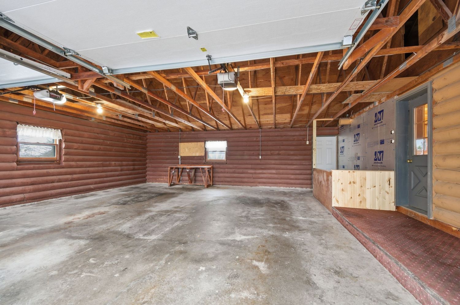 Large empty attic space with exposed wooden beams, rafters and brown walls shows potential for conversion or storage.
