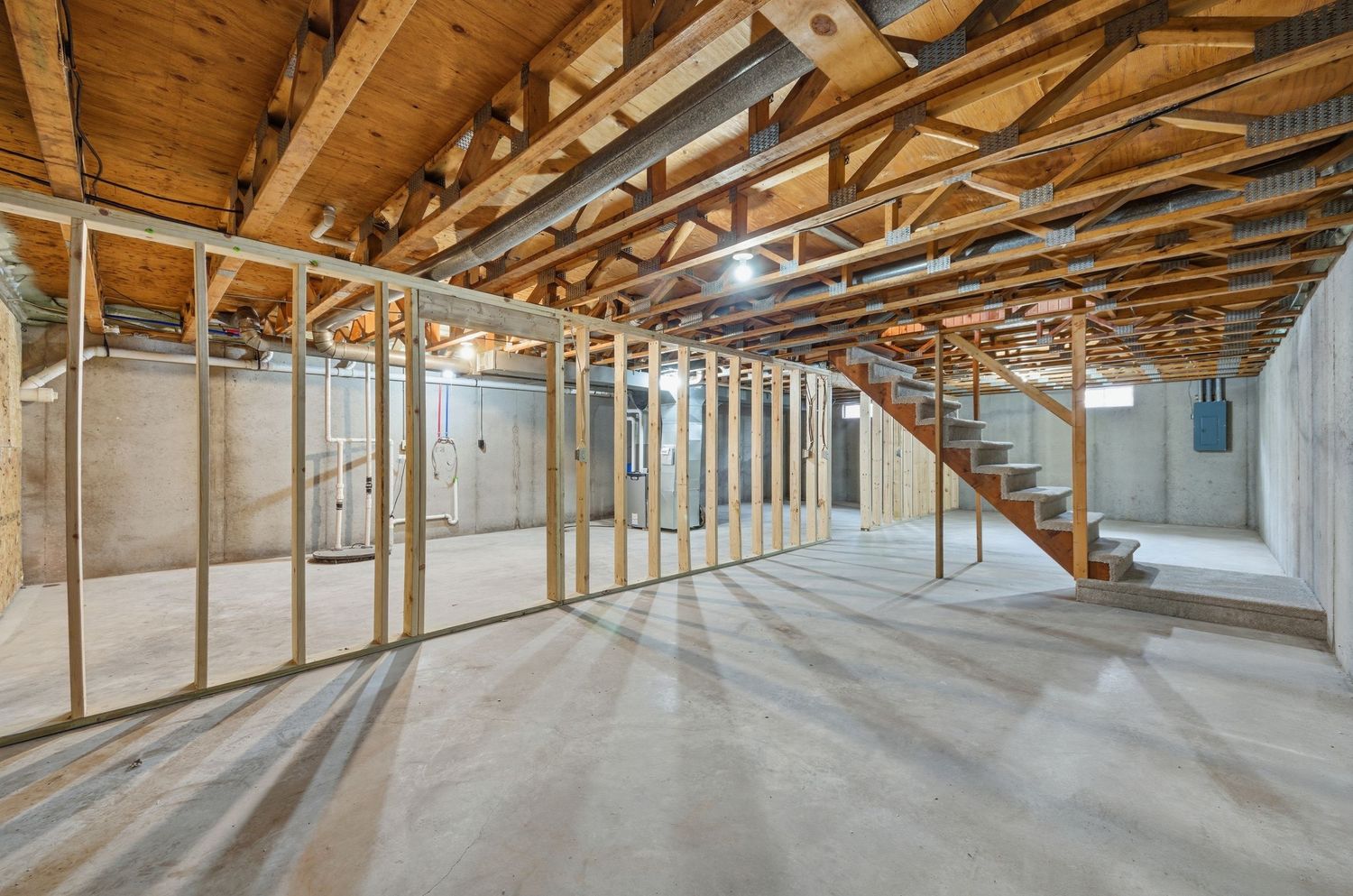 Interior view of unfinished building construction showing exposed wooden beams and rafters in a long corridor.