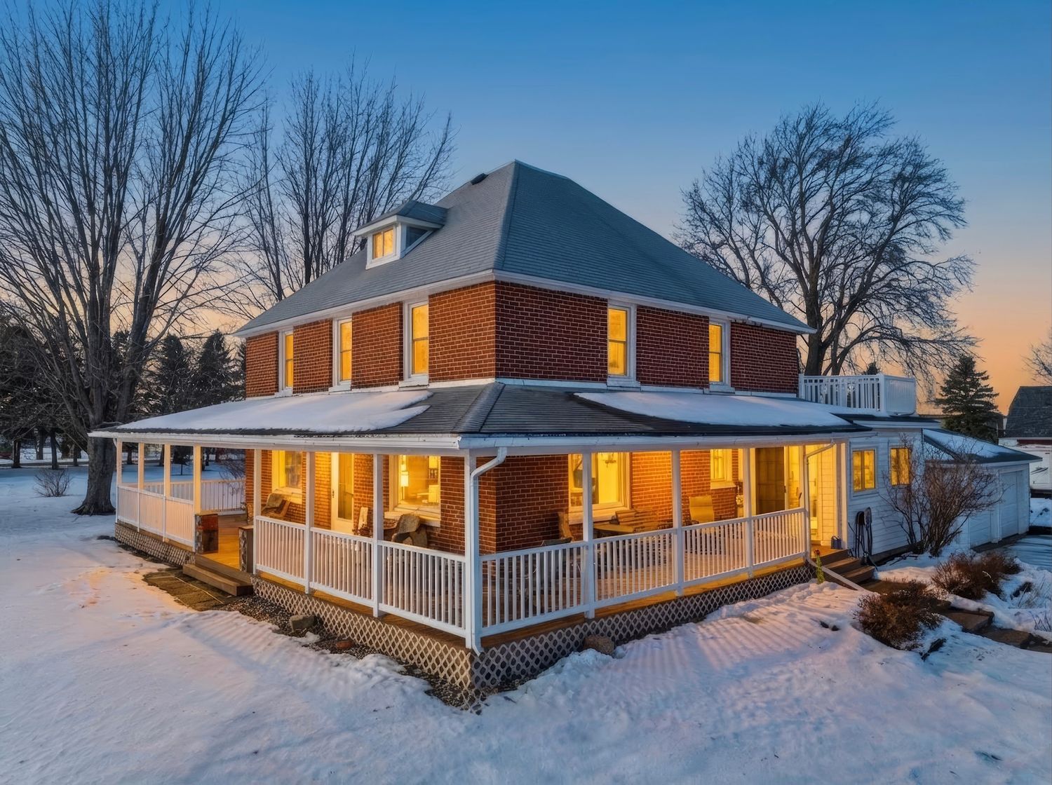 A panoramic sequence of a snow-covered ranch house with warm glowing windows at dusk shows different angles of the property.