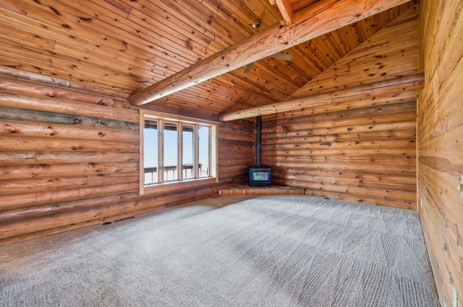 Interior view of a rustic wooden cabin ceiling with exposed beams and natural lighting.