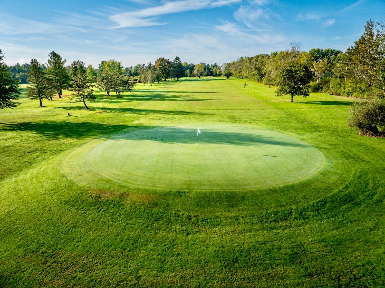 Marshfield County Club in Marshfield Wisconsin Rolling green golf course fairway with elevated putting green surrounded by trees. Bakerville