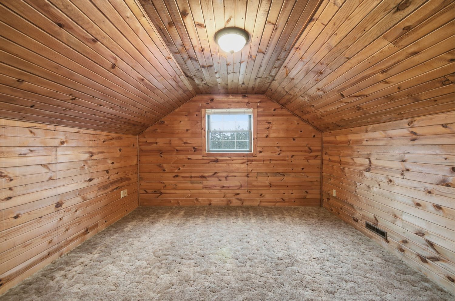 Rustic wooden paneled ceiling and walls create a warm, inviting interior space with natural lighting.