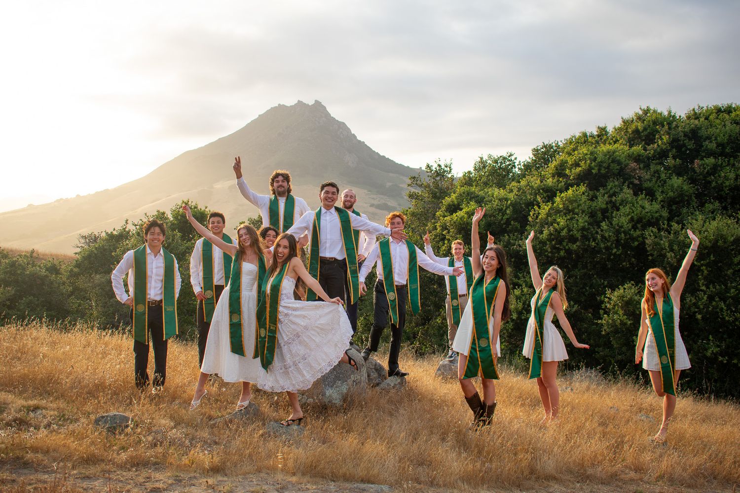 Wedding party poses in front of mountain landscape at golden hour.