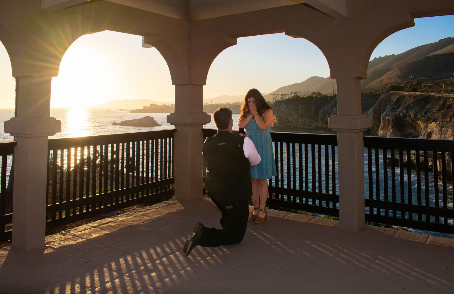 Scenic coastal view through arched colonnade during golden hour with long shadows.