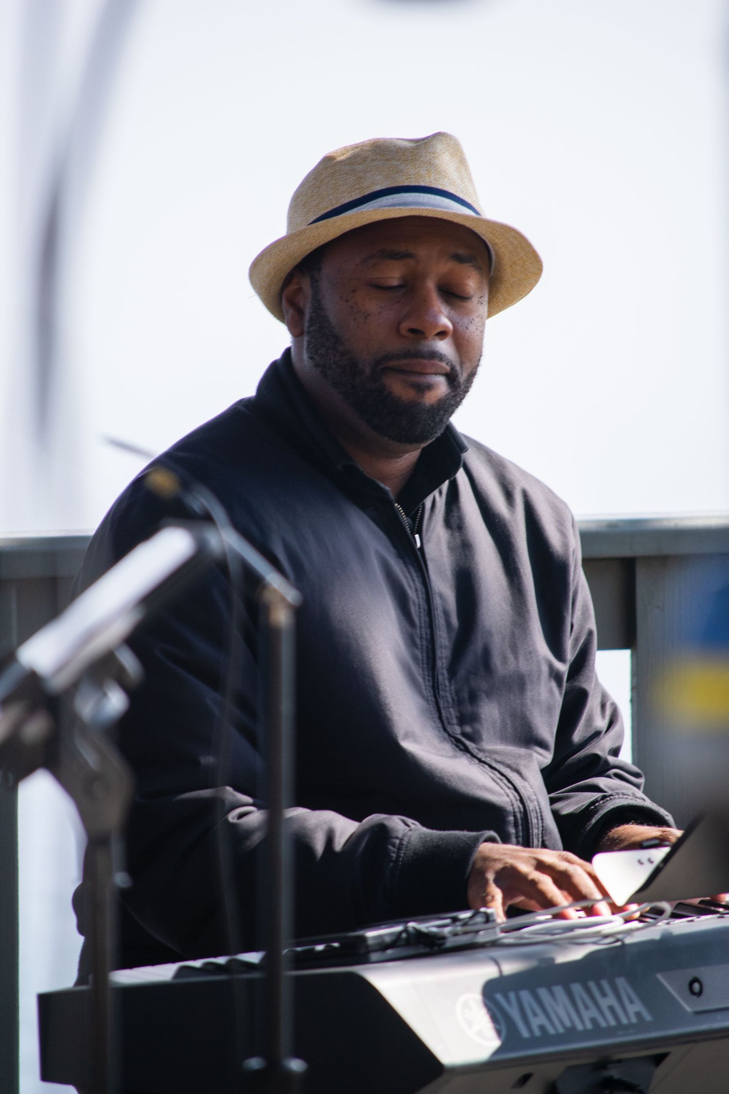 Musician in tan hat plays Yamaha keyboard during a performance.