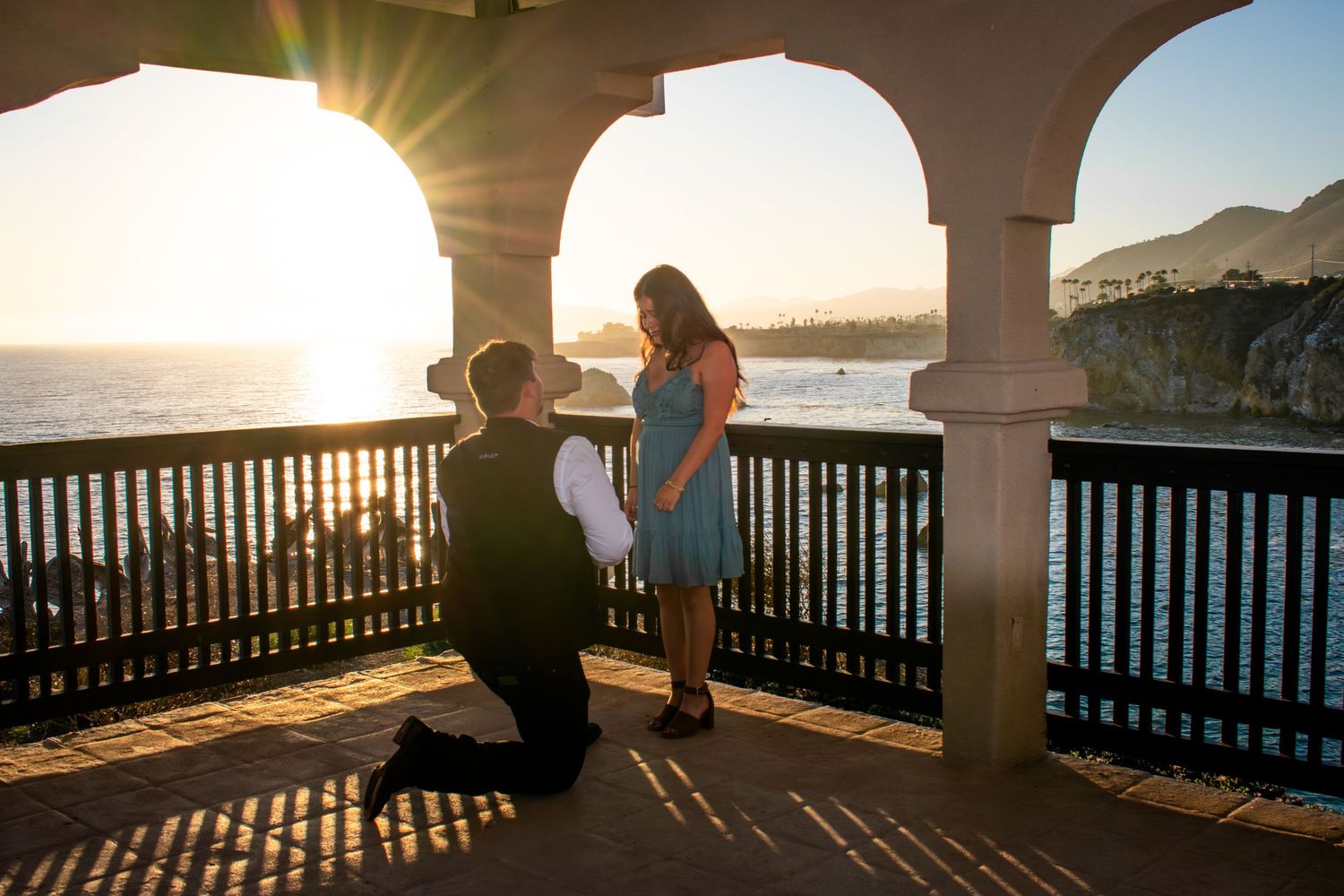 Silhouettes against ocean sunset viewed through Mediterranean-style archways.
