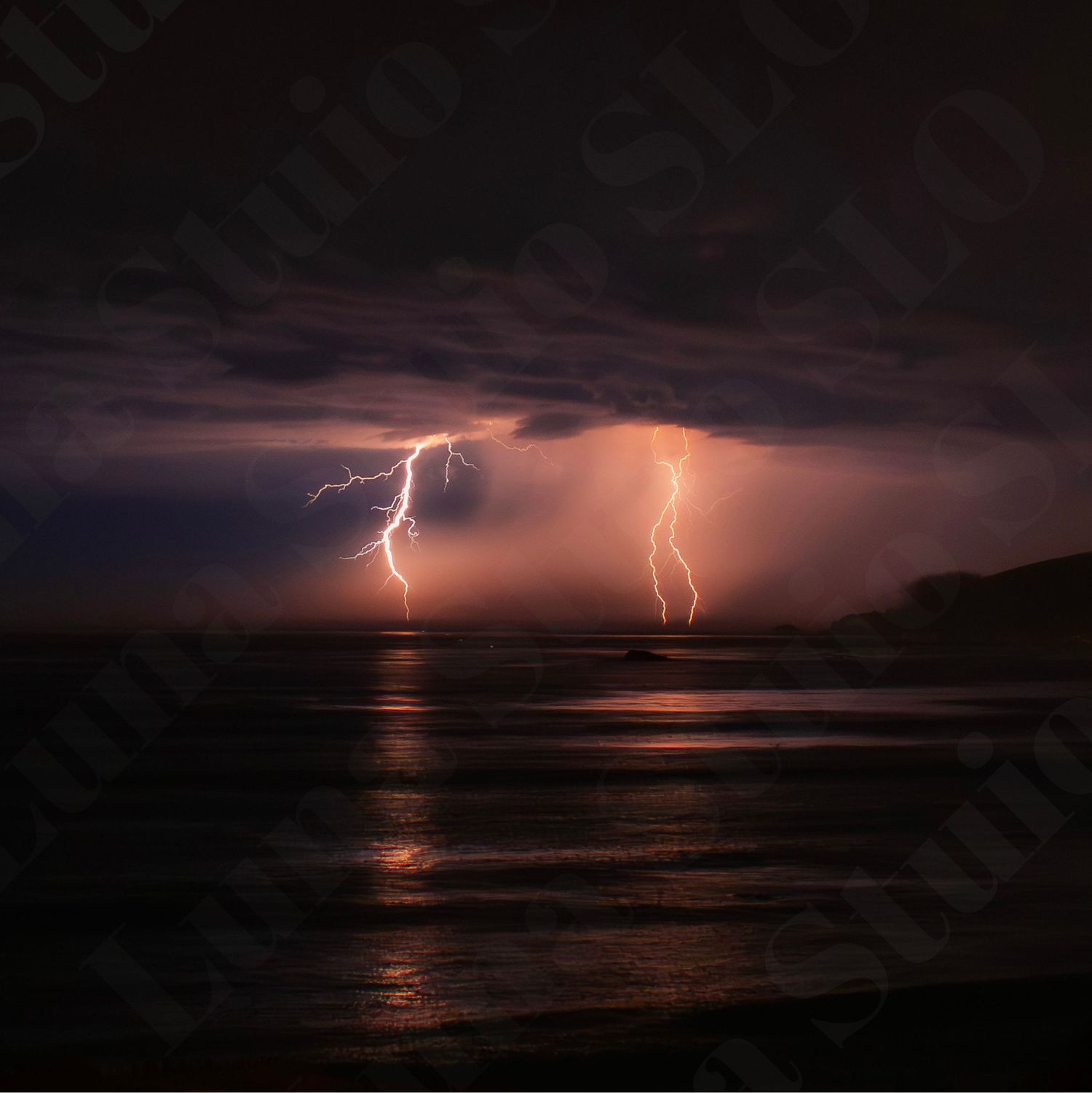 Dramatic lightning bolts illuminate a dark stormy seascape at night.