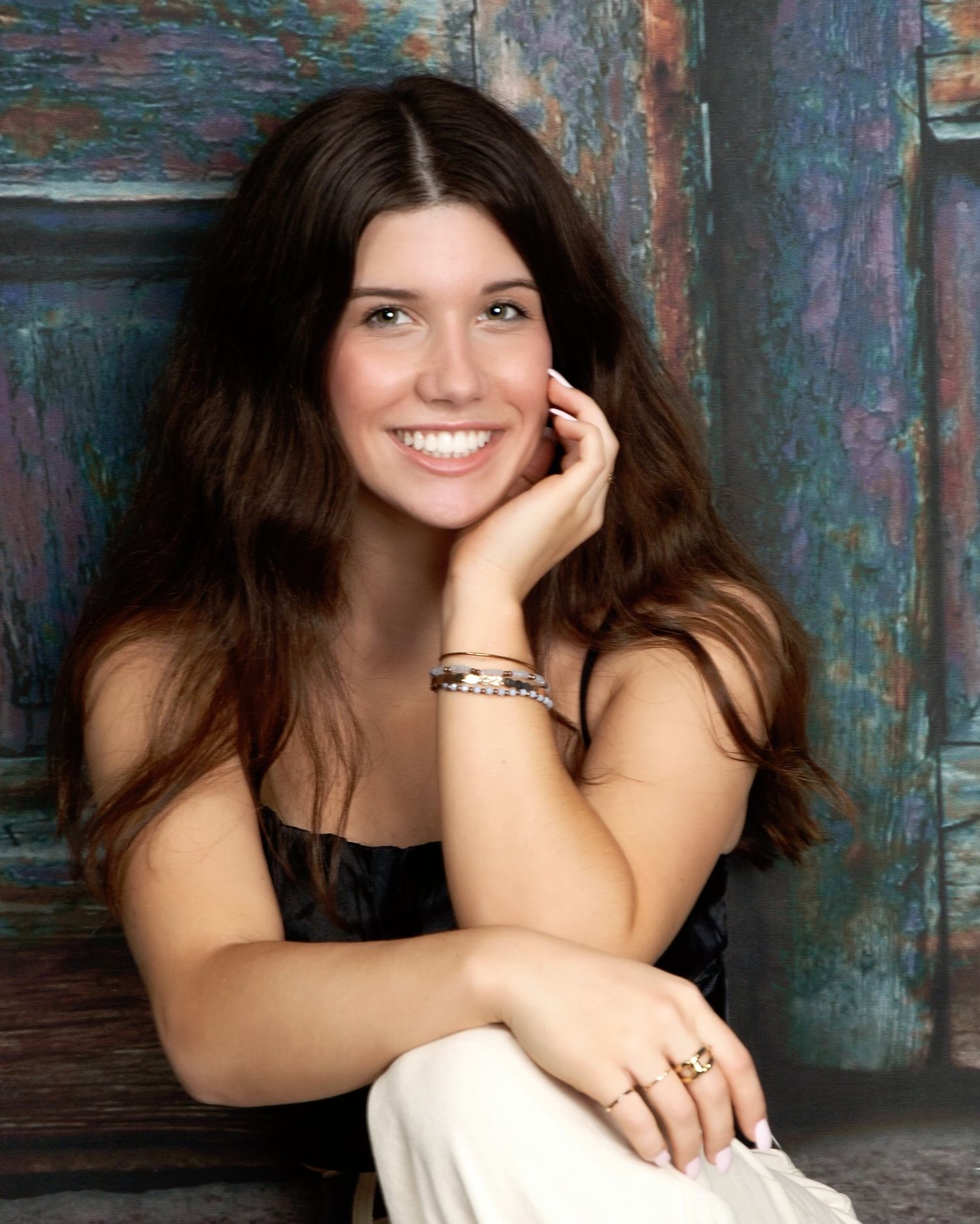 Portrait session against weathered blue wall background with artistic lighting.