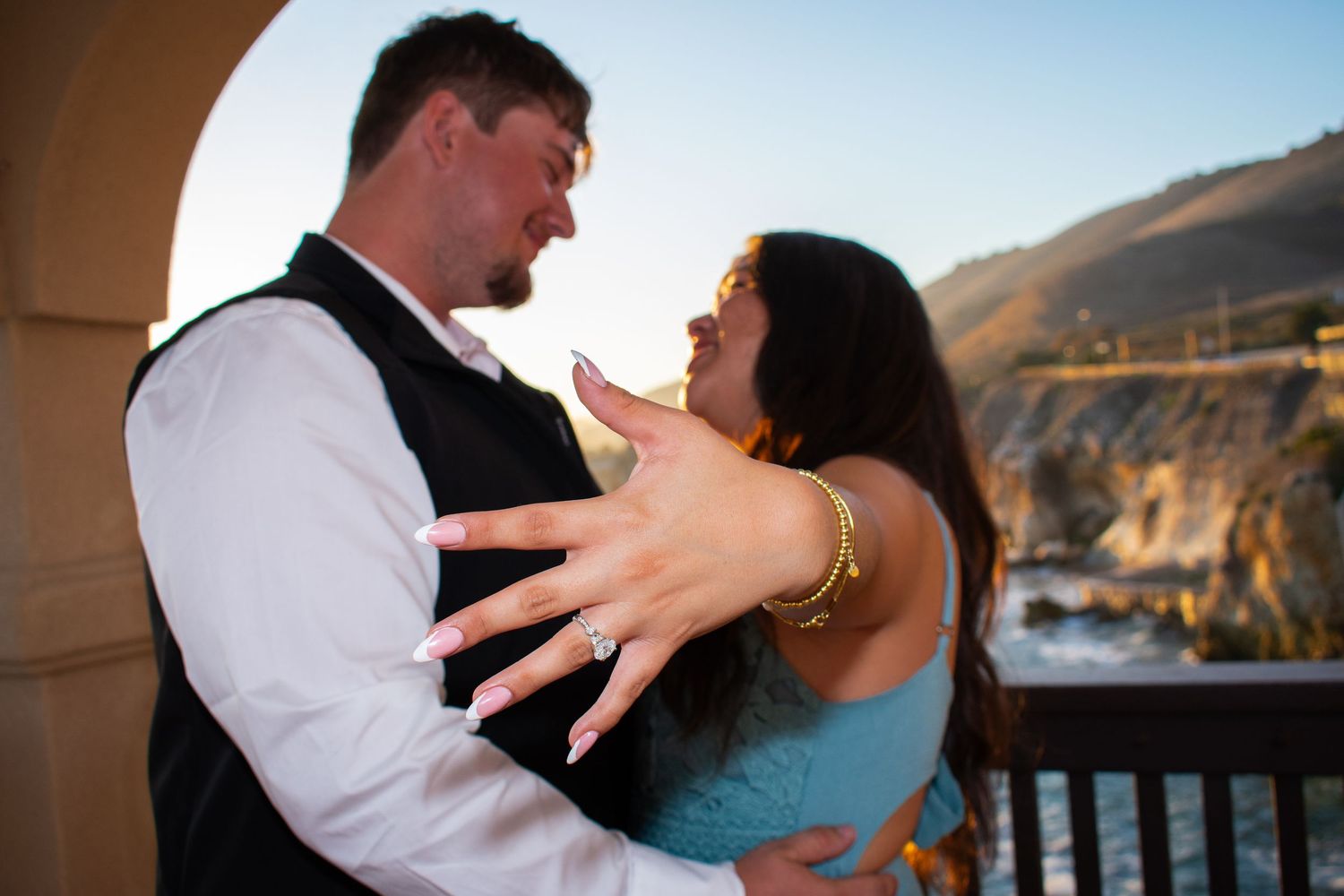 Couple dancing together on an oceanfront terrace with coastal views in the background.
