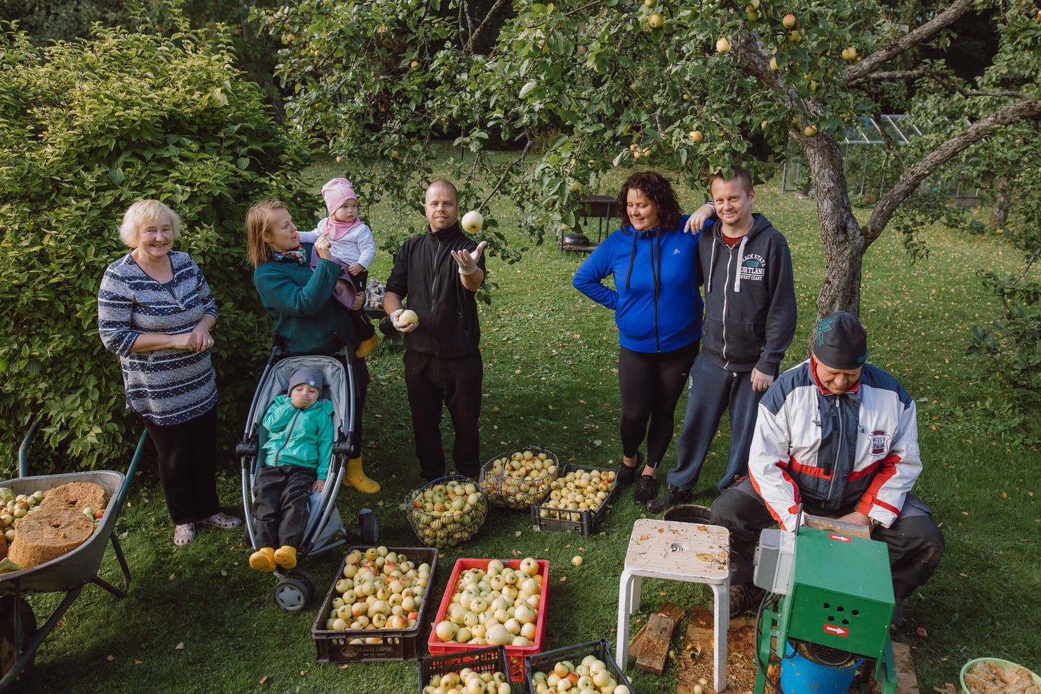 Group of people gathering outdoors around tables with fresh apples during harvest season.