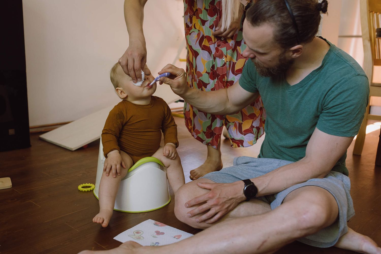 Parent and child work together on a creative craft project at a wooden table.