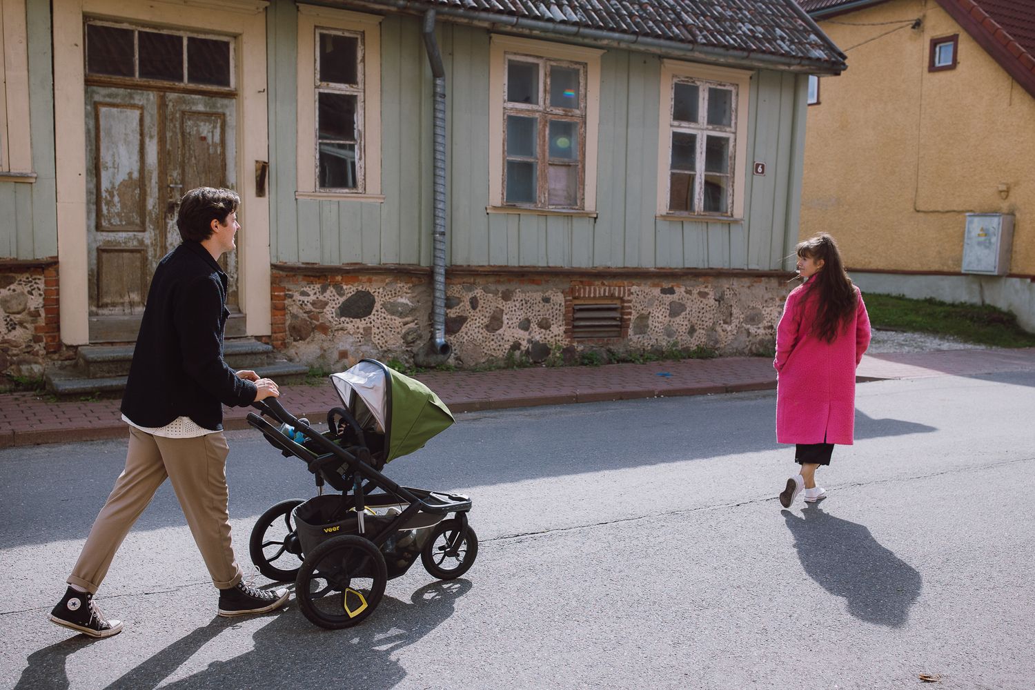 People walking on a street with a stroller on a cloudy day.