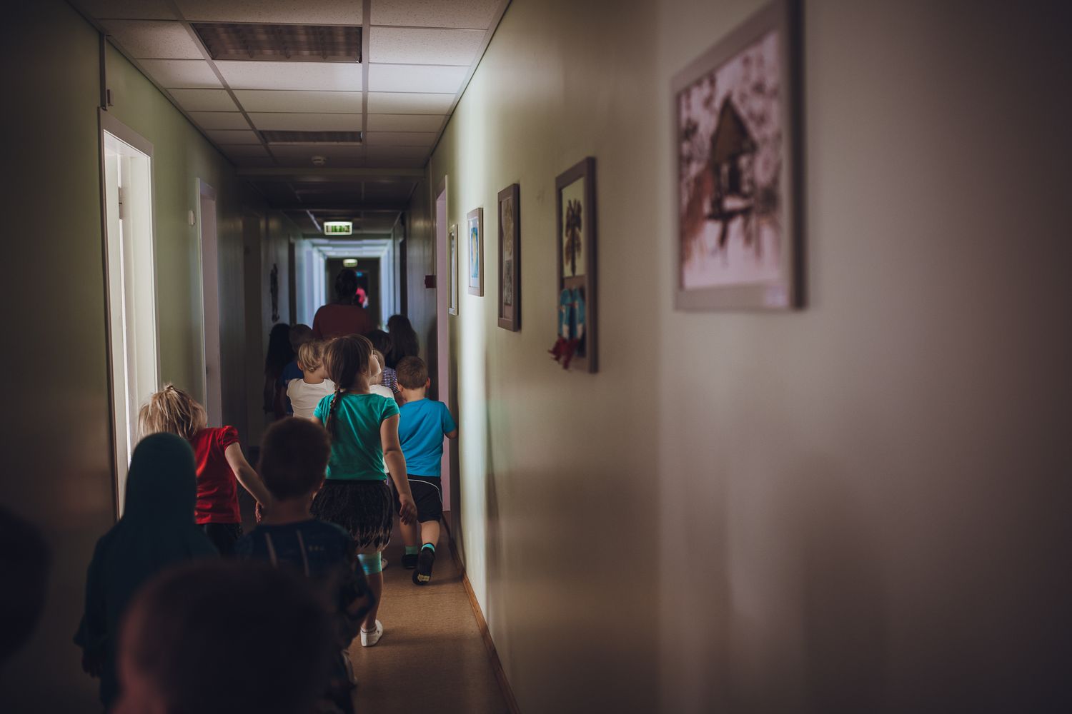 Long institutional hallway with dim lighting and framed artwork on the walls.