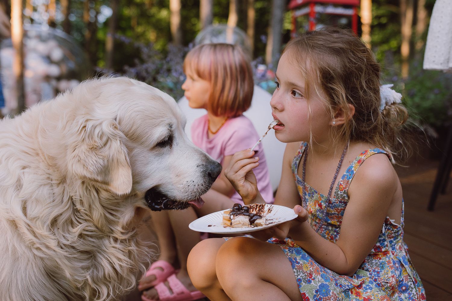 A fluffy white dog and children share a special moment outdoors on a sunny day.