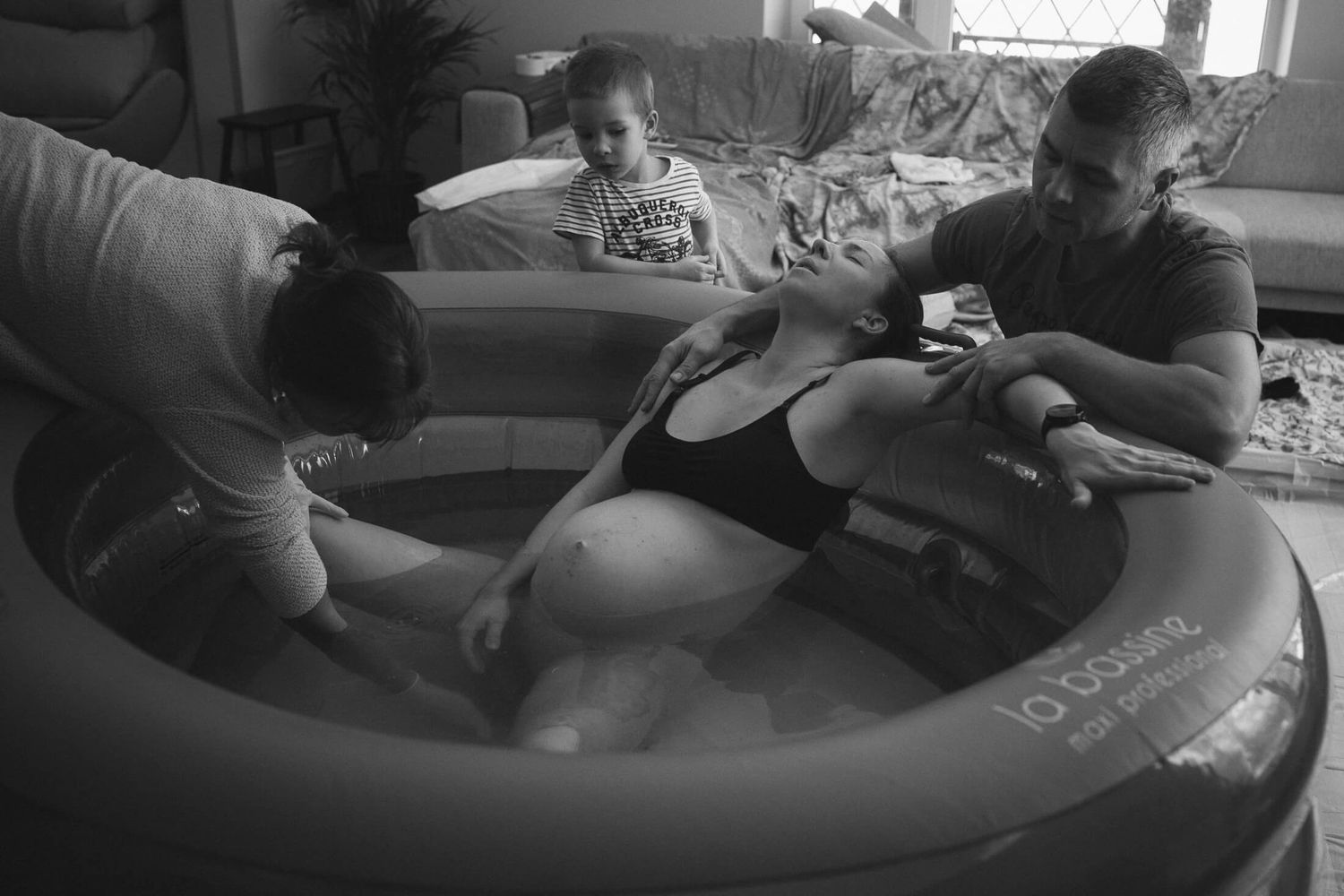 People gather around an inflatable birthing pool during labor preparation.