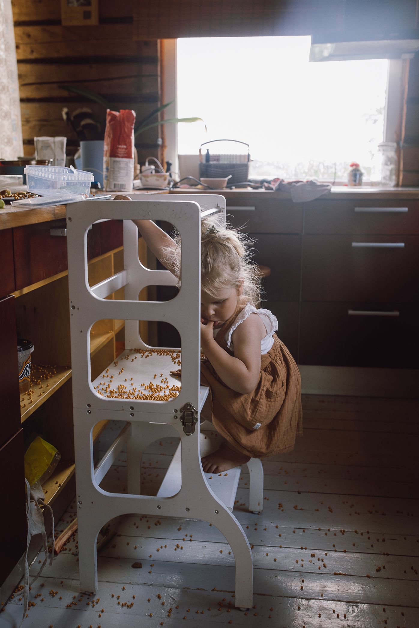 A series of white chairs in a rustic wooden room with scattered crumbs on the floor.