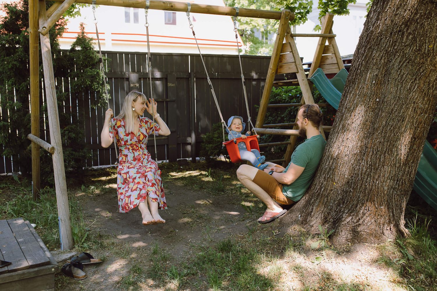 People enjoying a summer afternoon on backyard swings under a shady tree.